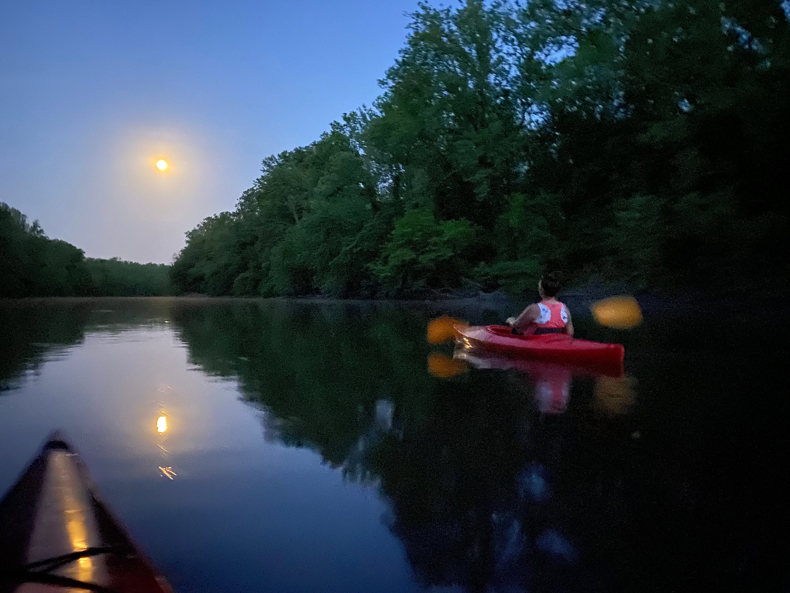 Full moon kayak paddling along the river at moonrise