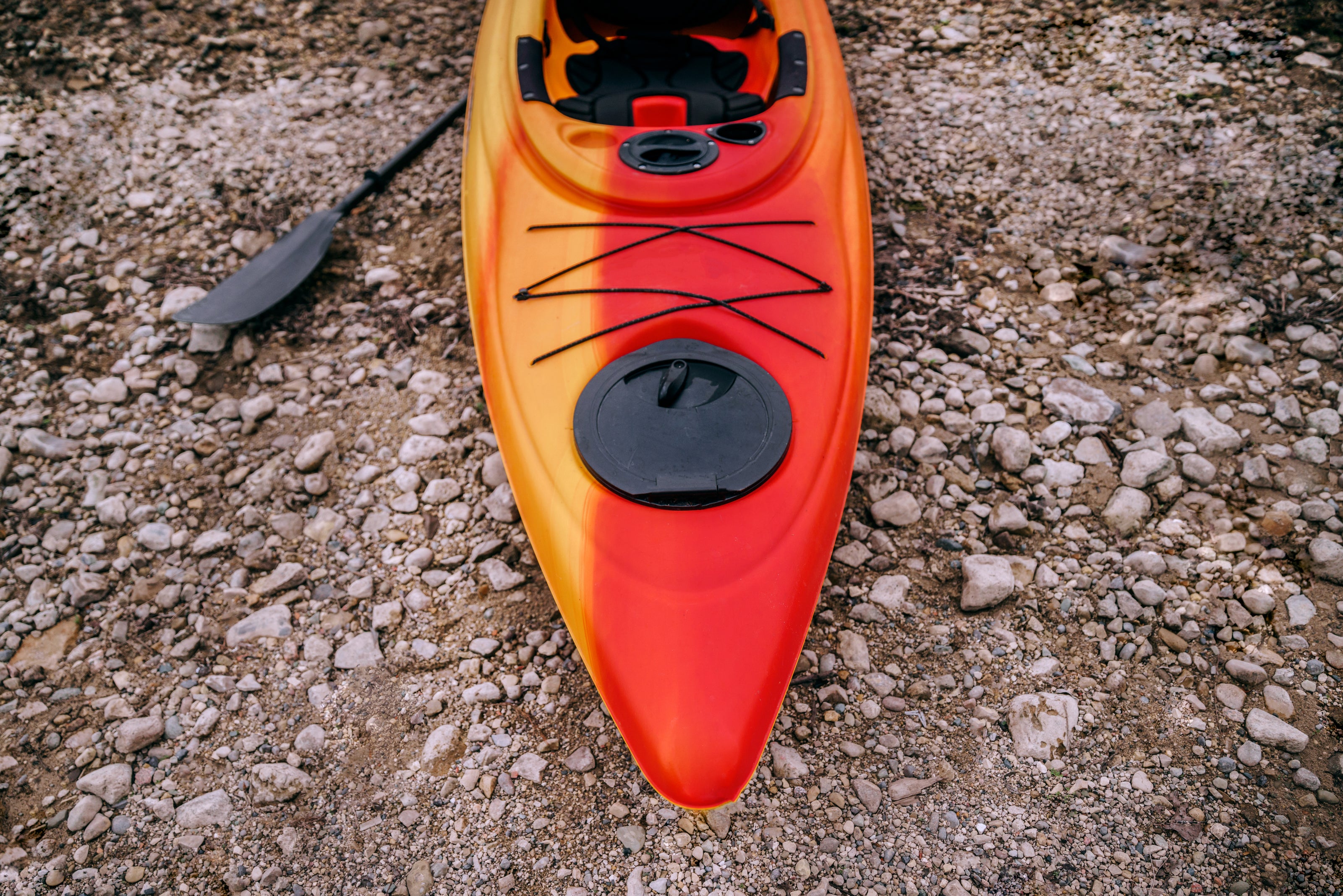 A close-up photo of a single red and orange kayak.